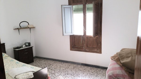 Interior view of a simple village house in Purchena, Almeria with a window and basic furnishings.