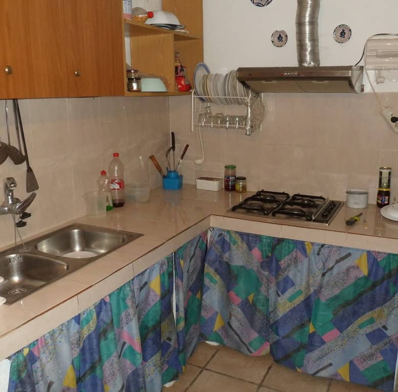 Cozy kitchen of a farm property in Baza, Granada, featuring a double sink, gas stove, and colorful c.