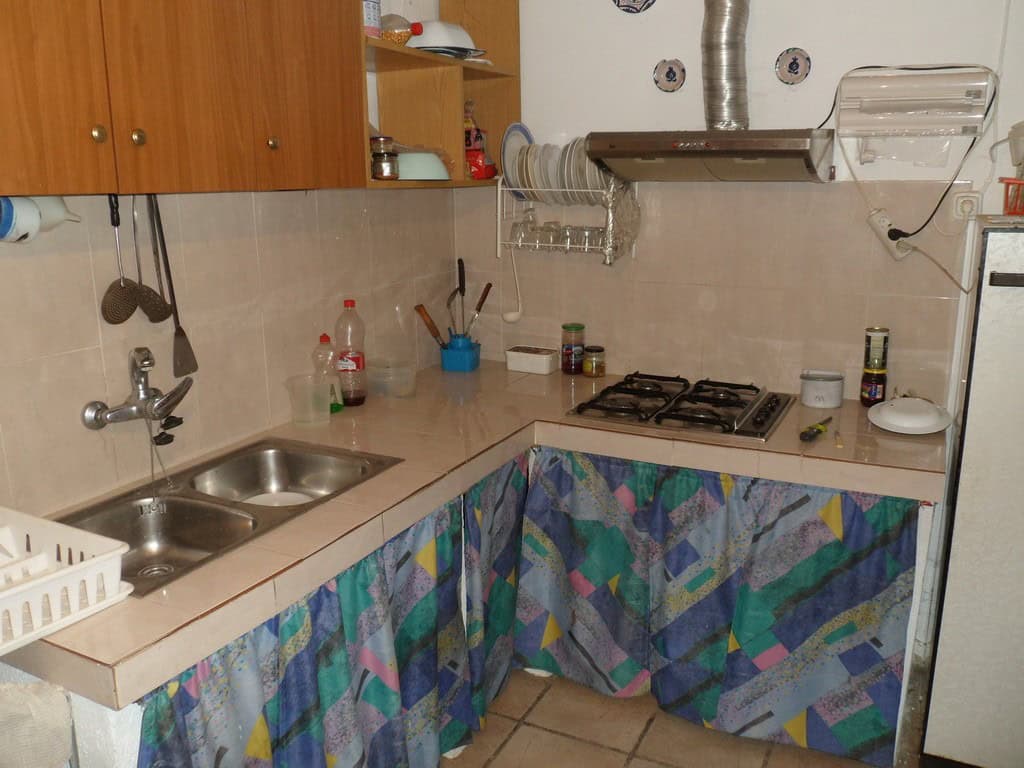 Cozy kitchen of a farm property in Baza, Granada, featuring a double sink, gas stove, and colorful c.