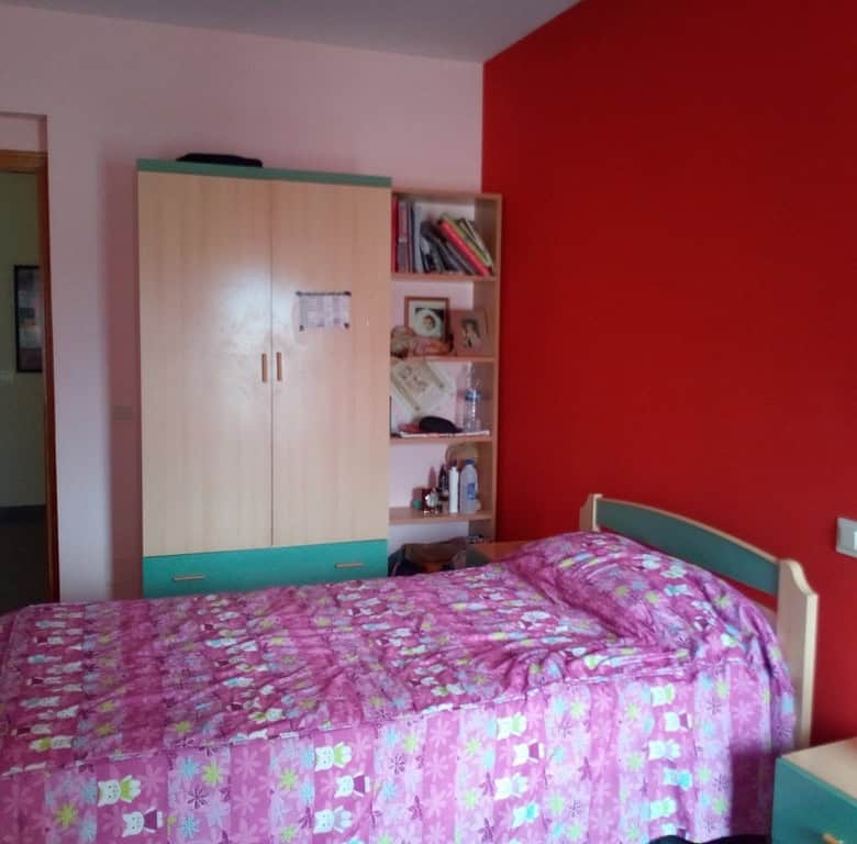 Bright bedroom with pink bedding and red accent wall in Cela village, Almeria.