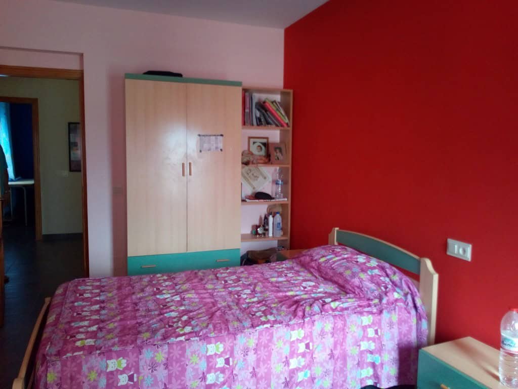 Bright bedroom with pink bedding and red accent wall in Cela village, Almeria.
