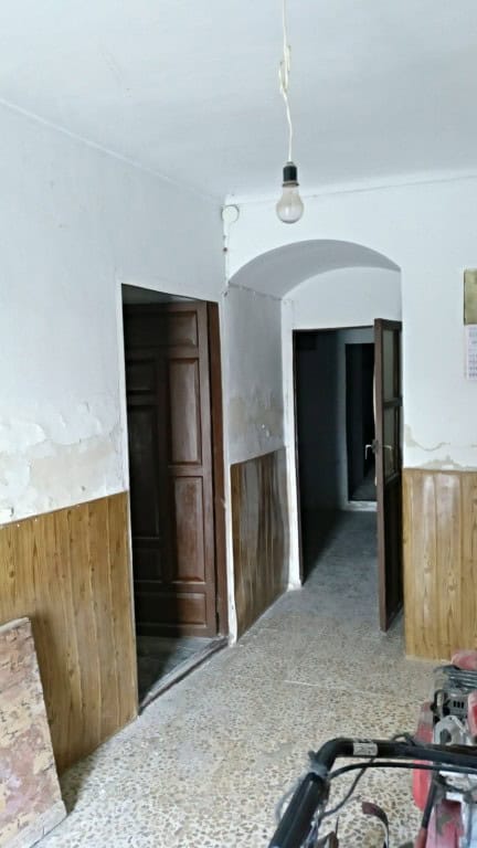 Interior view of a rustic rural property in La Alqueria, Granada, showing simple walls and doorways.