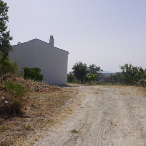 Rural property with a white house and dirt road in Castril, Granada, Spain.