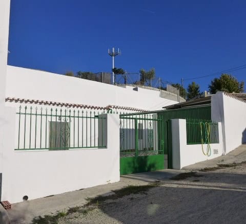 Traditional cave house in Galera, Granada with white walls and green gate.