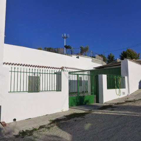 Traditional cave house in Galera, Granada with white walls and green gate.