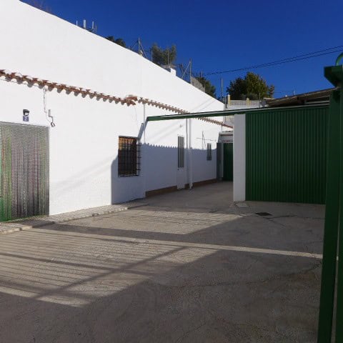 Cave house exterior in Galera, Granada with white walls and green gate under a clear blue sky.