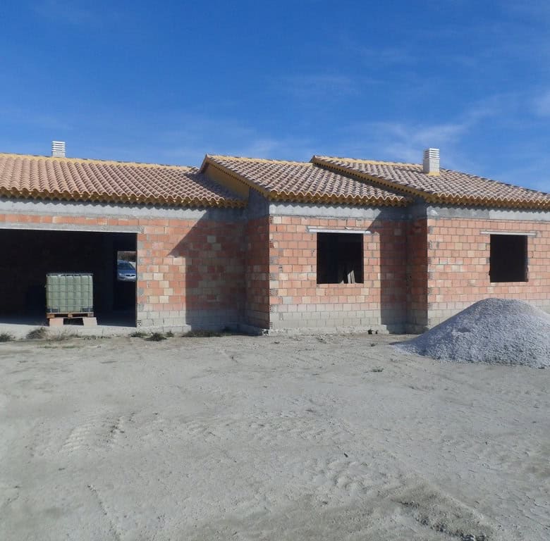 Farm property in Benamaurel, Granada, with unfinished brick walls and tiled roof, set against a clea.