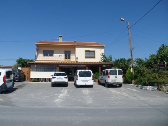 Commercial building in Baza, Granada, with parking area and surrounding greenery.