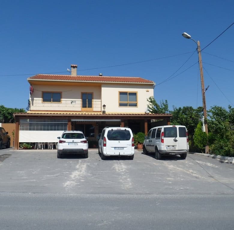 Commercial building in Baza, Granada, with parking area and surrounding greenery.