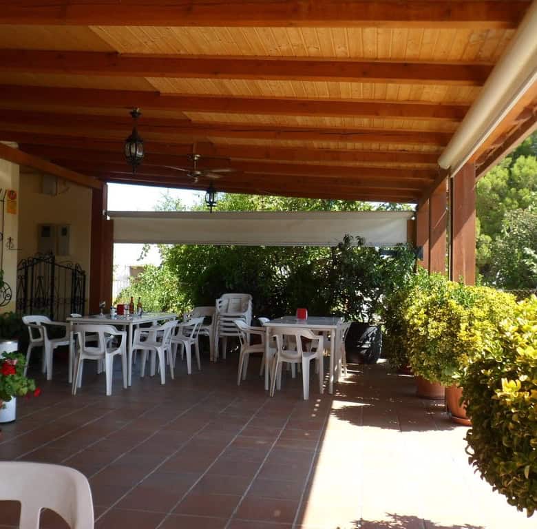 Outdoor dining space with wooden ceiling and lush greenery in Baza, Granada.