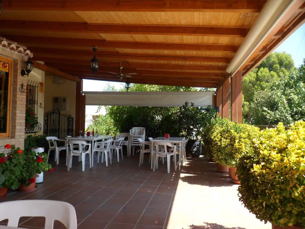 Outdoor dining space with wooden ceiling and lush greenery in Baza, Granada.