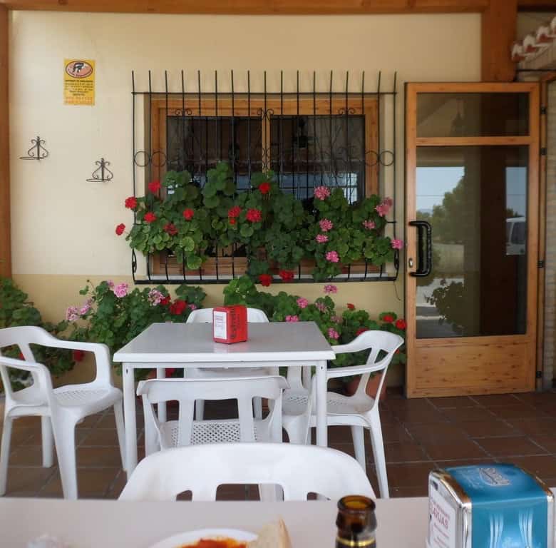 Outdoor patio in Baza, Granada with colorful flowers and seating area.