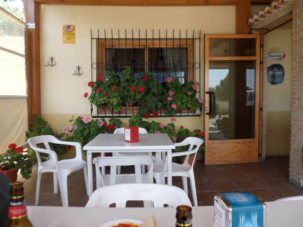 Outdoor patio in Baza, Granada with colorful flowers and seating area.