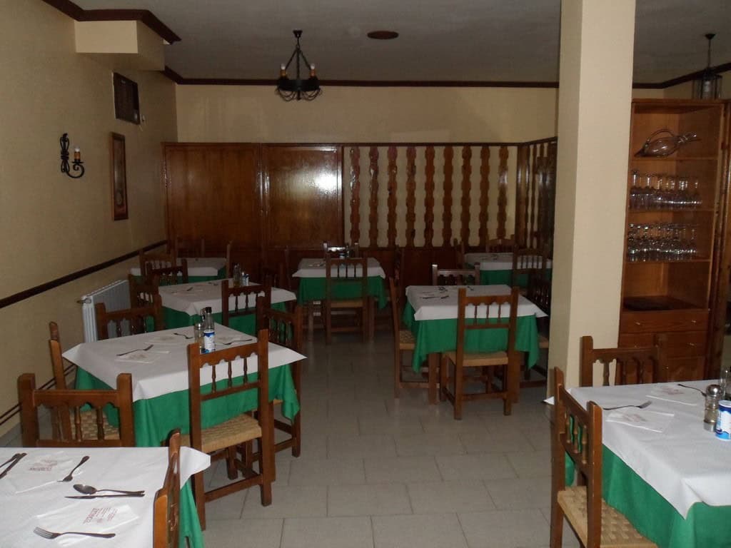Interior of a traditional restaurant in Baza, Granada, featuring wooden furniture and green tableclo.