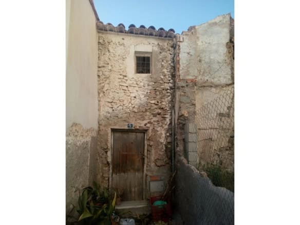 Traditional village house in Bayarque, Almeria, with rustic stone walls and a wooden door.