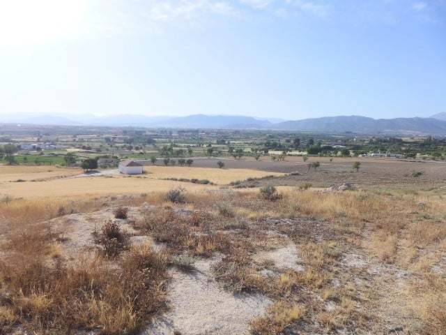 Cave house located in Baza, Granada, set in a scenic rural landscape with open fields and distant mo.