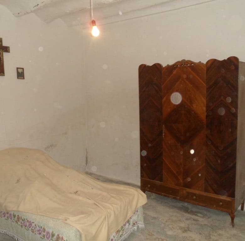 Charming bedroom in a rural property in Baza, Granada, featuring a simple bed, wooden wardrobe, and.