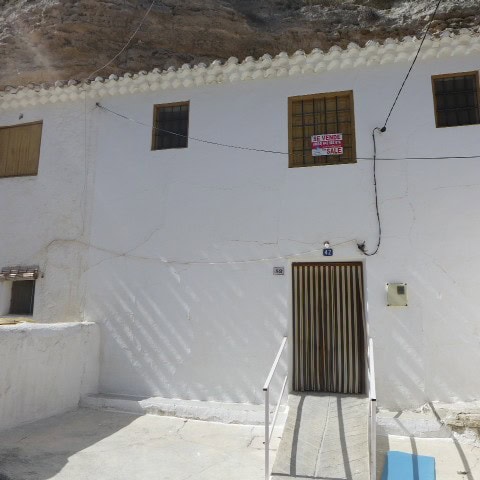 Traditional cave house in Galera, Granada, with whitewashed walls and rustic wooden windows.
