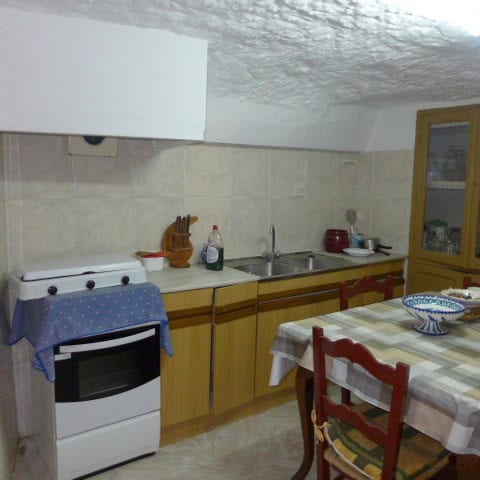 Cozy cave house kitchen with rustic wooden cabinets and modern appliances in Galera, Granada.