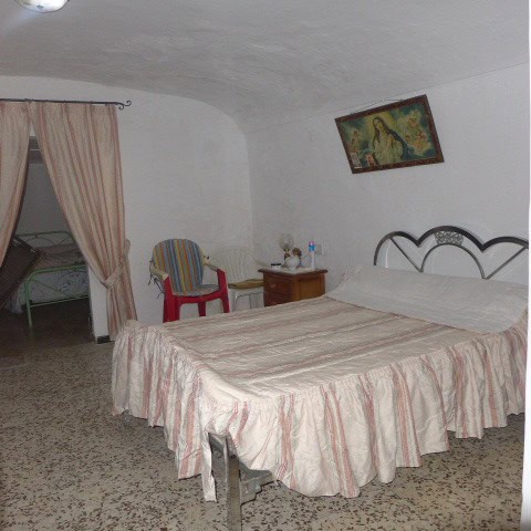 Charming cave house bedroom with rustic decor in Galera, Granada, featuring a comfortable bed and tr.
