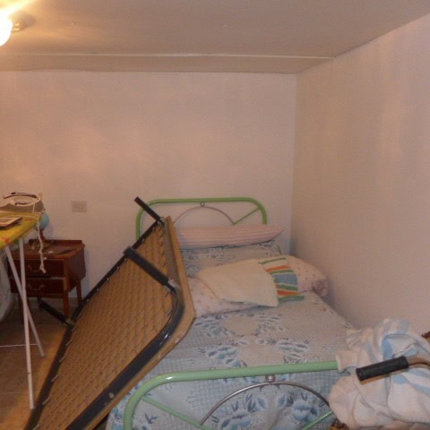 Cave house interior in Galera, Granada, featuring a bed with colorful pillows and simple furnishings.