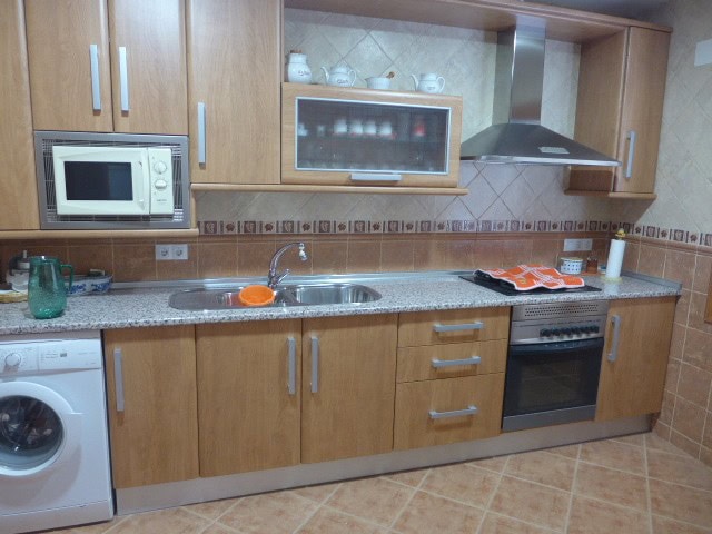 Cozy kitchen in a modern apartment in Freila, Granada, featuring wooden cabinets, a stove, and essen.