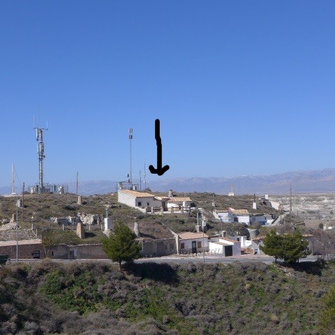 Cave house in Orce, Granada with communication antennas and scenic mountain views.