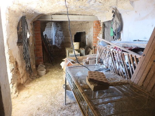 Cave house interior in Orce, Granada, showing rustic stone walls and construction materials.