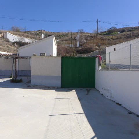Traditional cave house with white walls and green gate in Orce, Granada, Spain.