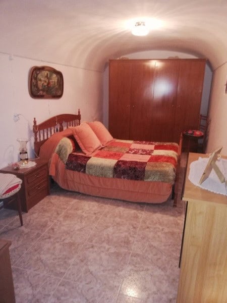 Charming cave house bedroom with rustic decor in Orce, Granada, featuring a comfortable bed and vint.