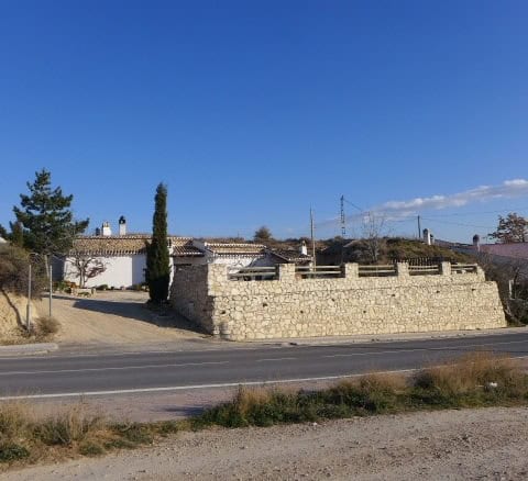 Cave house in Huescar, Granada with traditional stone walls and scenic surroundings.