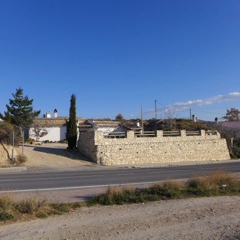 Cave house in Huescar, Granada with traditional stone walls and scenic surroundings.