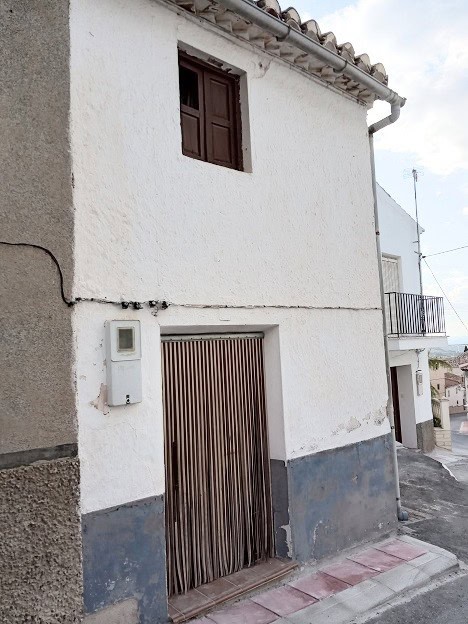 Town house in Gor, Granada with traditional white exterior and wooden door.