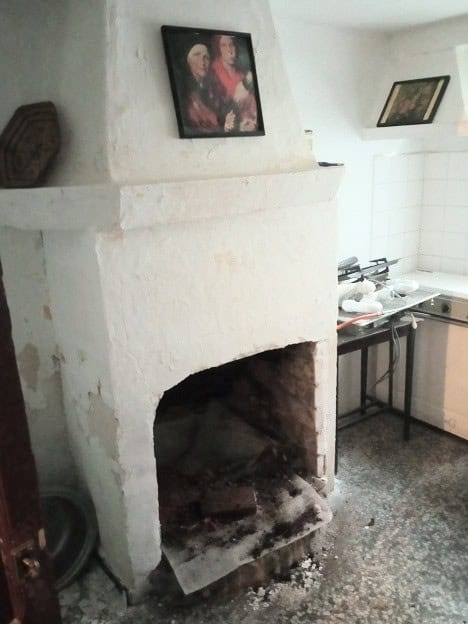 Fireplace in Gor town house, Granada, with traditional white plaster walls and rustic charm.