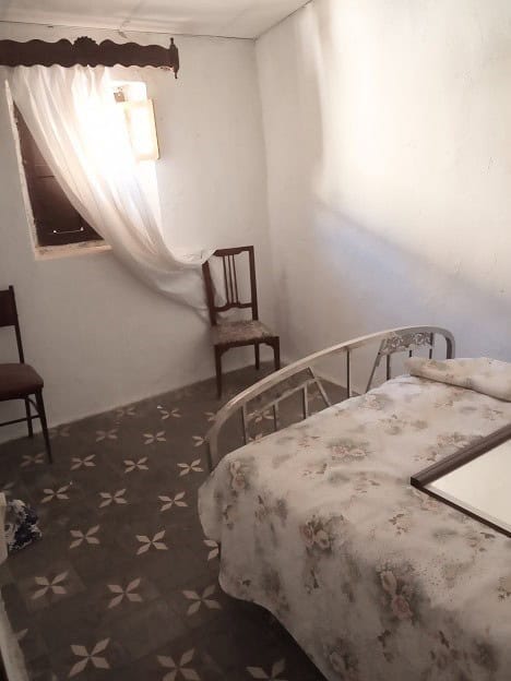 Cozy bedroom in a traditional town house in Gor, Granada, featuring a simple bed, wooden chairs, and.