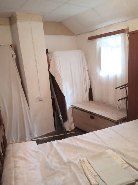 Cozy interior of a town house in Gor, Granada, featuring a simple bedroom with a window and storage.