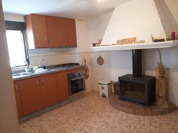 Charming village property kitchen in Gor, Granada with wooden cabinets, modern appliances, and a tra.