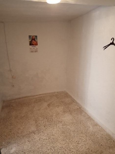Cozy village room in Gor, Granada with simple decor and religious poster on the wall.