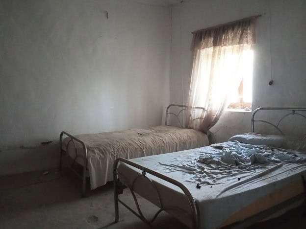 Simple bedroom with two beds in a rural property in Belerda, Jaen, featuring natural light from a wi.