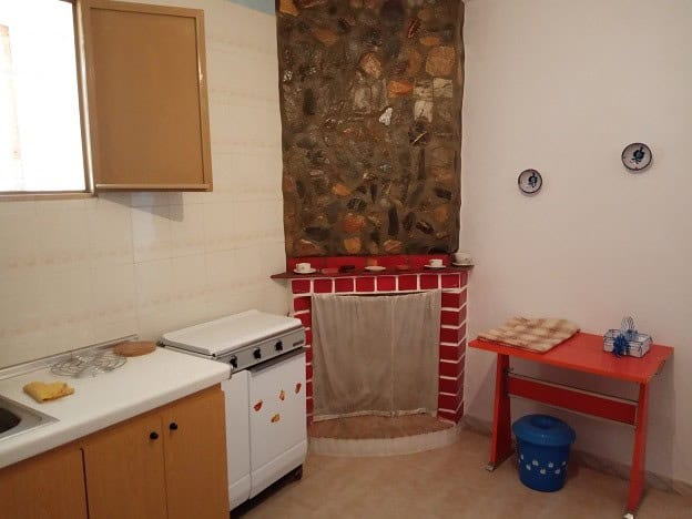 Cozy rural property kitchen in Gor, Granada with rustic stone fireplace and simple furnishings.
