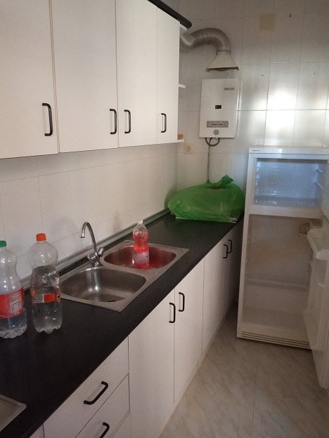 Compact kitchen with white cabinets and black countertop in Gor, Granada.