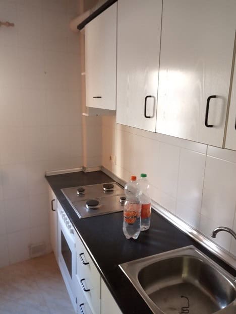 Bright kitchen with white cabinets and black countertop in Gor, Granada.
