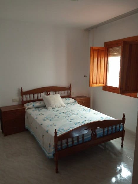 Interior view of a bedroom in Gor, Granada apartment with wooden window shutters and simple furnishi.