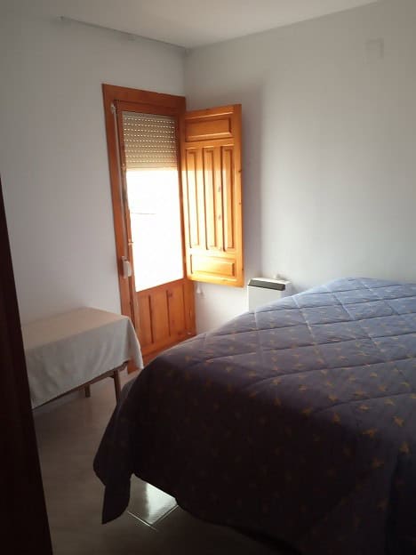 Apartment interior with bed and wooden window in Gor, Granada.