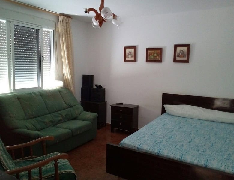 Cozy bedroom with a double bed and living area in a charming village property in Armuna, Almeria.
