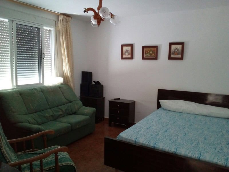 Cozy bedroom with a double bed and living area in a charming village property in Armuna, Almeria.
