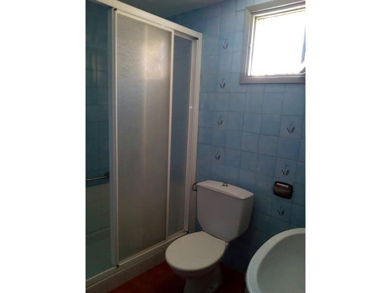 Cozy bathroom with shower, toilet, and small window in Armuna village property.