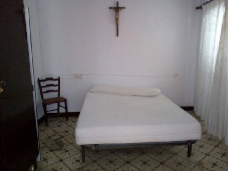 Bedroom with simple furnishings and a crucifix on the wall in Armuna, Almeria.