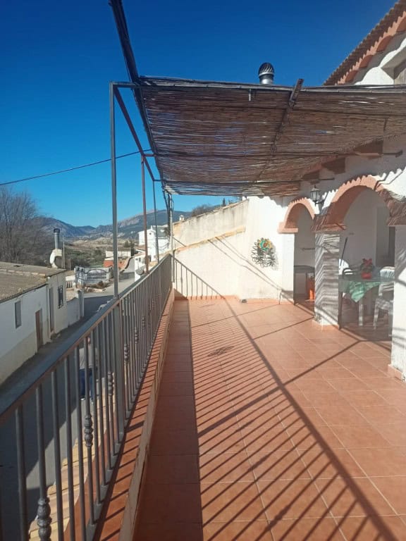 Balcony view of a cave house in Fontanar, Jaen with terracotta tiles and shaded patio.