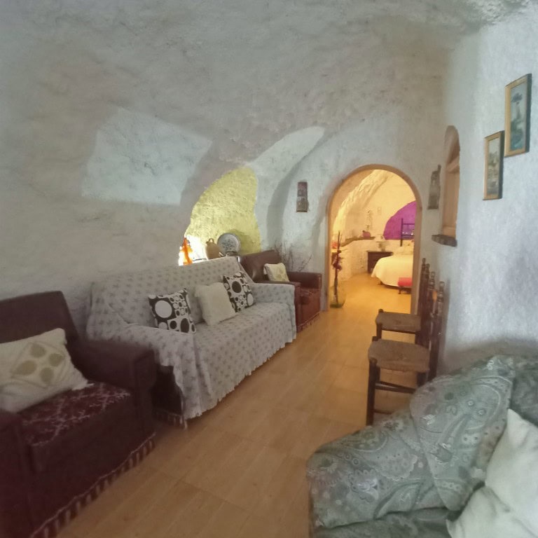Charming cave house interior in Fontanar, Jaen, featuring rustic stone walls and cozy furnishings.